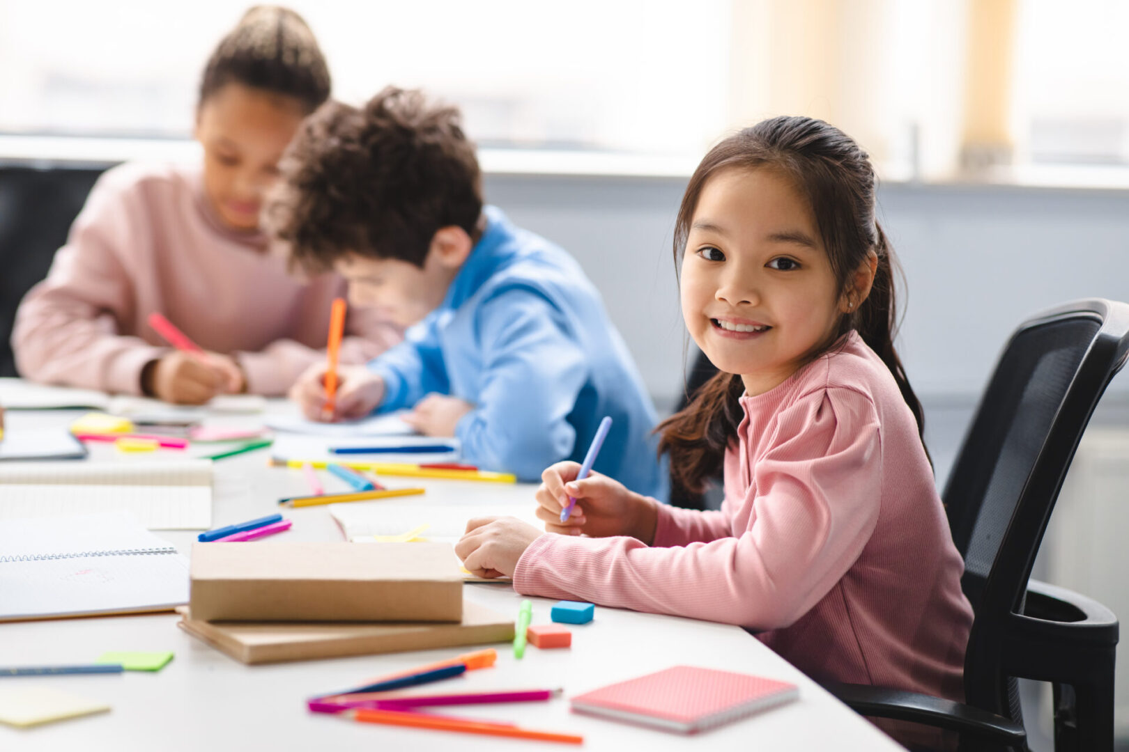 A group of children sitting at a table with pencils